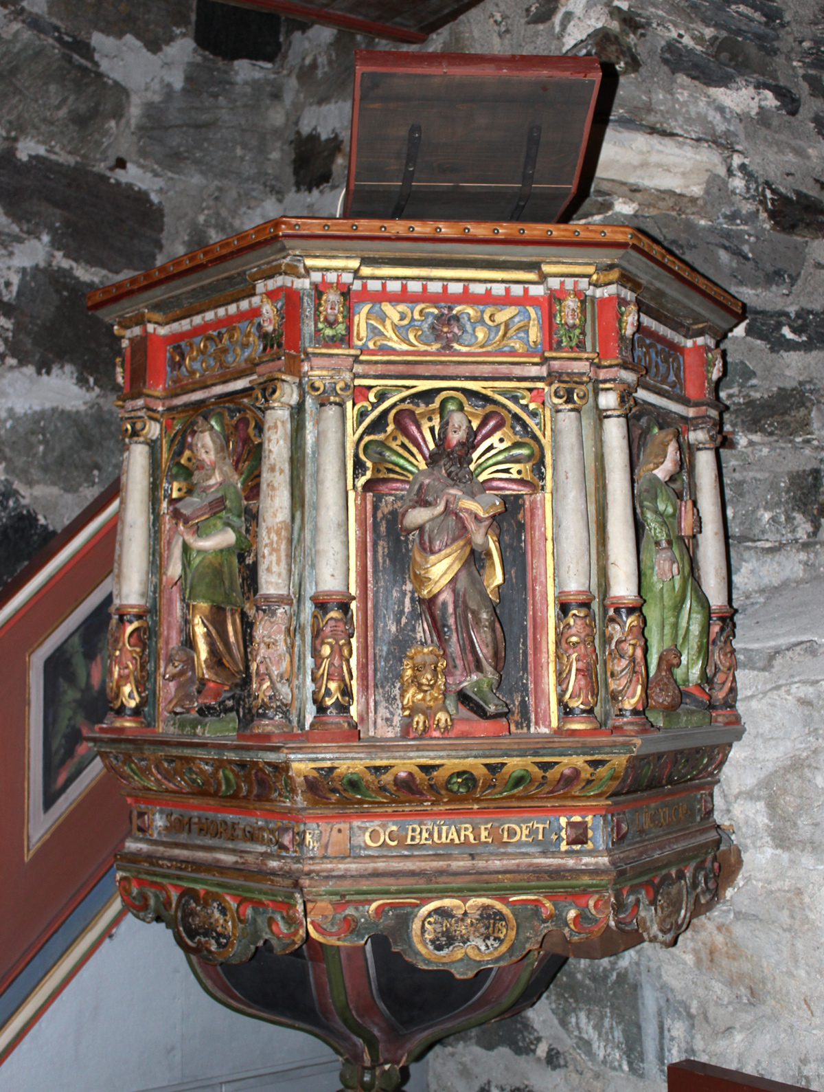 Altertavle i Logtun kirke, utskåret i 1652 og malt i 1655, med detaljerte figurer og utsmykking, plassert mot en steinvegg.
