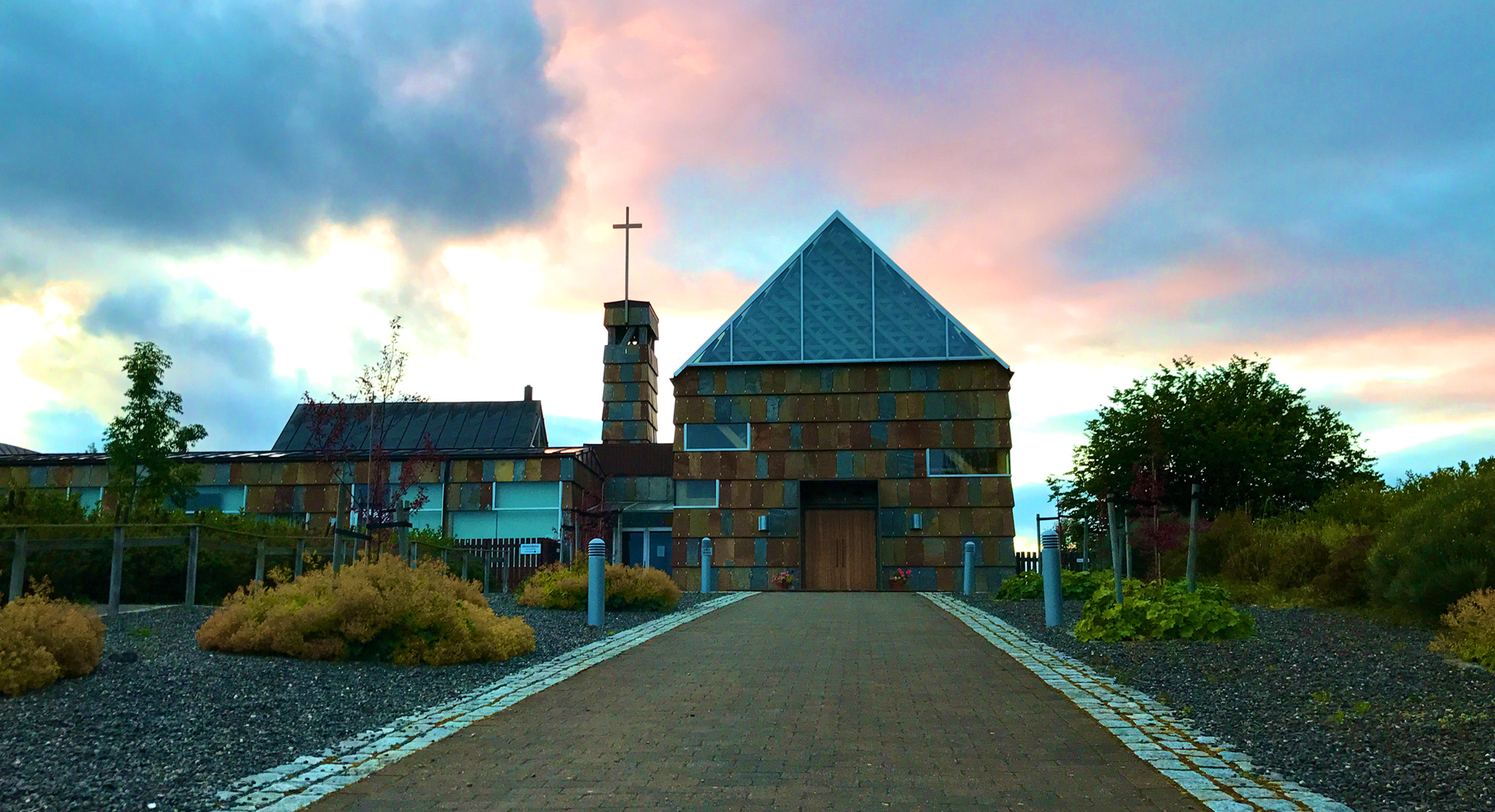 Tautra Mariakloster, et moderne katolsk kvinnekloster, med en unik arkitektur under en fargerik himmel.