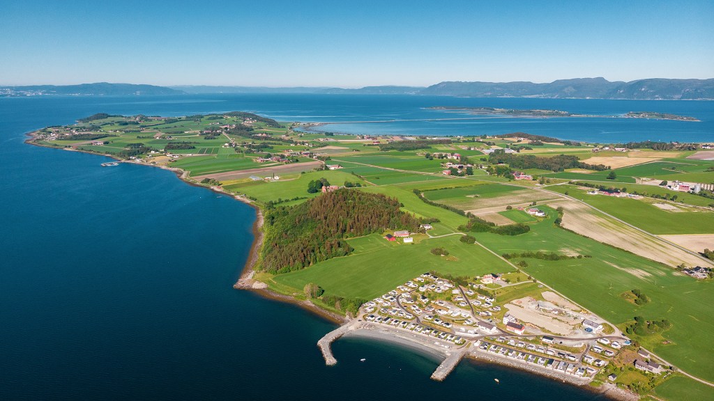 Oversiktsbilde av Frosta med frodige åkre, campingplasser og utsikt mot fjorden.