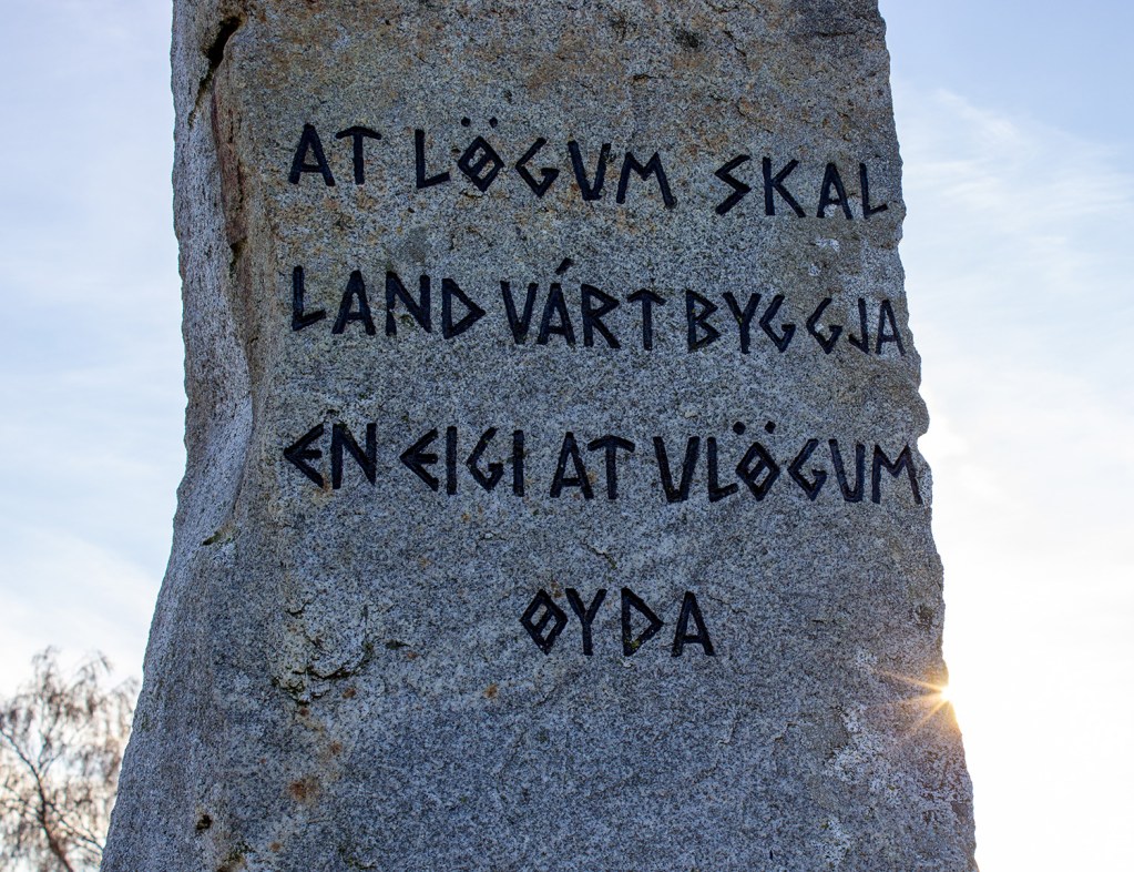 Bautastein med inskripsjon om Frostatinget, omgitt av sollys.
